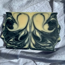 Load image into Gallery viewer, Two black and white swirled soap bars on a textured fabric background