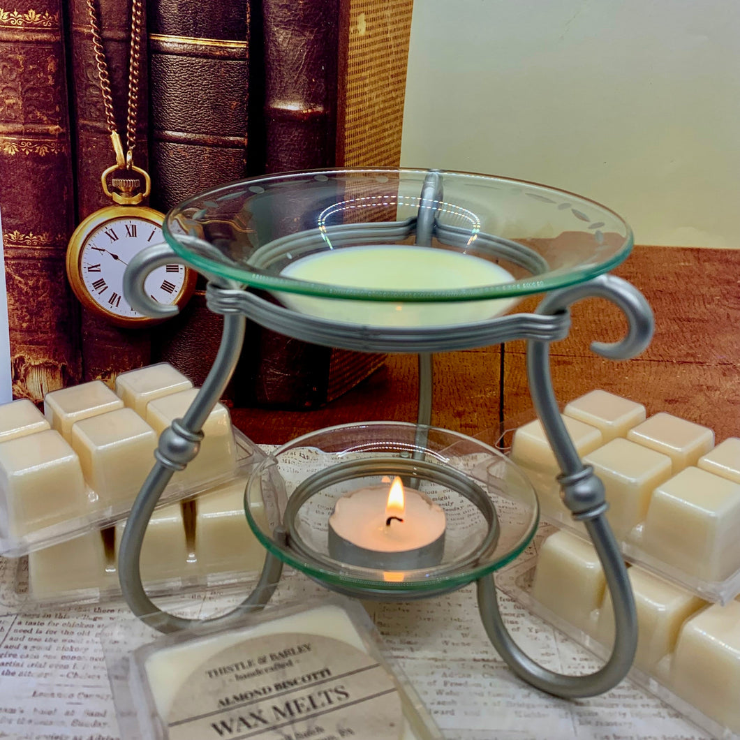 Wax melter with a lit candle surrounded by wax melts and books in the background